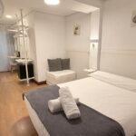 Cama de matrimonio en habitación doble con ropa de cama blanca